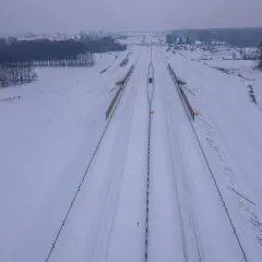 Zimowy krajobraz wokół budowanej drogi ekspresowej S1. Śnieg pokrywa pobocza i pola, tworząc białą pustkę.