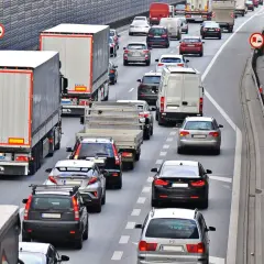 Kork na autostradzie, gdzie trwa jazda na suwak. Samochody i ciężarówki stoją w długim korku.