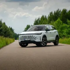 Biały, nowoczesny beijing samochód na tle zielonego lasu i błękitnego nieba.