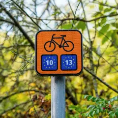 Pomarańczowy znak rowerowy z numerami 10 i 13, wskazujący trasę R10.