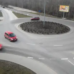 Rondo turbinowe jak jeździć? Czerwone samochody poruszają się po wielopasmowym rondzie, pokazując płynność ruchu.