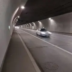 Biały samochód mknie przez oświetlony tunel zakopianka.