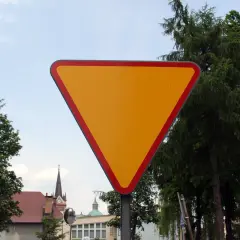 Żółty trójkątny znak a7 z czerwoną obwódką, ostrzegający o ustąpieniu pierwszeństwa.