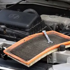 Klucz na zużytym filtrze powietrza, gotowy do wymiany w silniku samochodu.