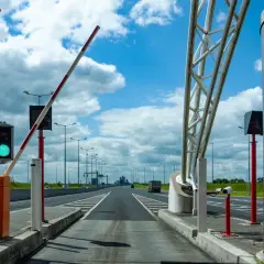 Brama na autostradzie A4 otwarta, zielone światło. Droga prowadzi w dal pod błękitnym niebem z chmurami.