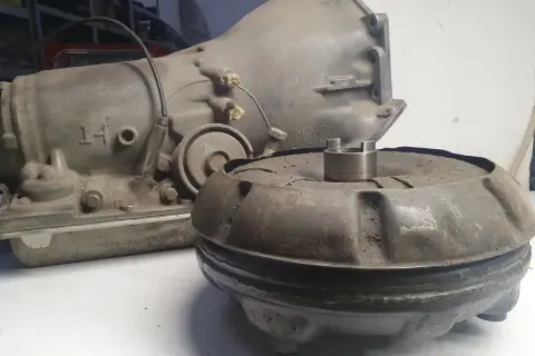 Zużyty sprzęgło hydrokinetyczne i skrzynia biegów leżą na stole.