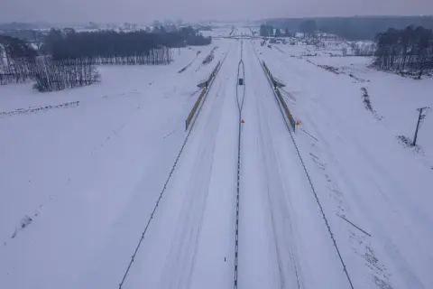 Zimowy krajobraz wokół budowanej drogi ekspresowej S1. Śnieg pokrywa pobocza i pola, tworząc białą pustkę.
