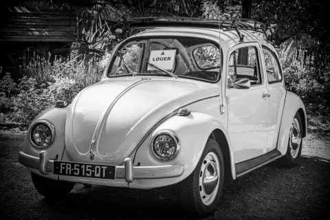 Klasyczny Volkswagen Garbus z tabliczką "À LOUER" na przedniej szybie. Idealny do kupna samochodu na wakacje.