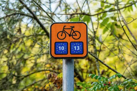 Pomarańczowy znak rowerowy z numerami 10 i 13, wskazujący trasę R10.