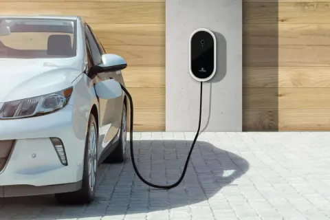 Biały samochód elektryczny podłączony do ładowarki ściennej. Czysta energia dla przyszłości.