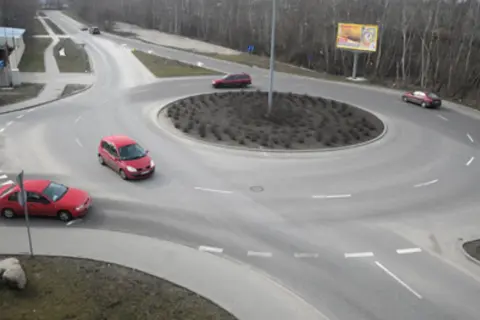 Rondo turbinowe jak jeździć? Czerwone samochody poruszają się po wielopasmowym rondzie, pokazując płynność ruchu.