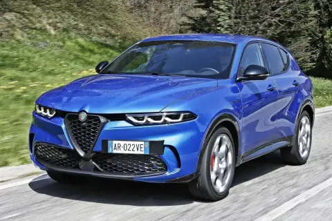 Niebieski Alfa Romeo Tonale pędzi po drodze. Wśród wielu marek samochodów alfabetycznie, ten włoski SUV wyróżnia się dynamicznym designem.
