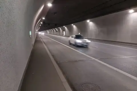 Biały samochód mknie przez oświetlony tunel zakopianka.