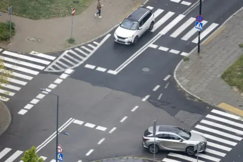 Na skrzyżowaniu równorzędnym dwa samochody zbliżają się do pasów.
