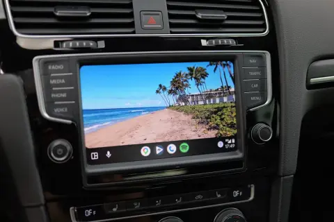 Samochód z ekranem Android Auto aktualizacja. Widok na tropikalną plażę z palmami.