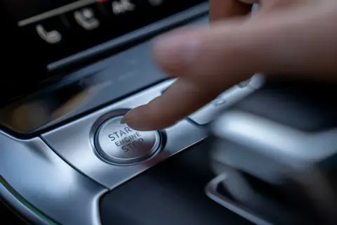 Palec naciska przycisk "START ENGINE STOP", rozpoczynając lub kończąc podróż.