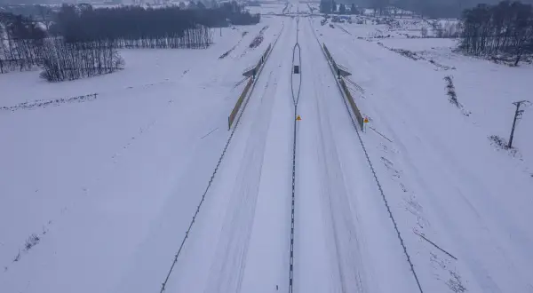 Zimowy krajobraz wokół budowanej drogi ekspresowej S1. Śnieg pokrywa pobocza i pola, tworząc białą pustkę.