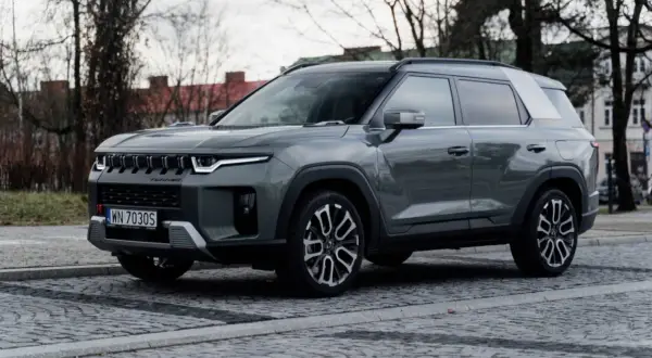 Szary SsangYong Torres, nowoczesne auto z charakterystycznym grillem, zaparkowane na brukowanej ulicy.