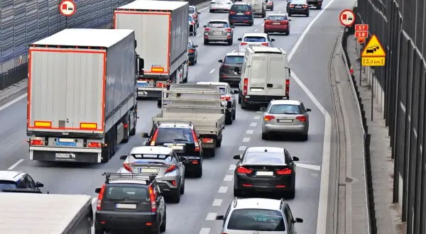 Kork na autostradzie, gdzie trwa jazda na suwak. Samochody i ciężarówki stoją w długim korku.
