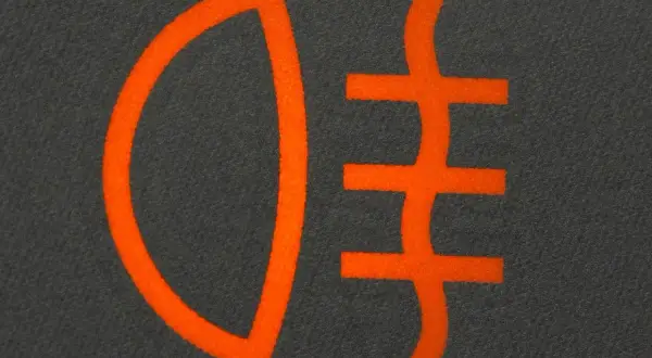 Pomarańczowy symbol świateł do jazdy dziennej na ciemnym tle.