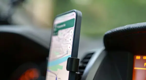 Smartfon z mapą na ekranie, zamontowany w samochodzie. To darmowa nawigacja samochodowa, która ułatwia podróżowanie.