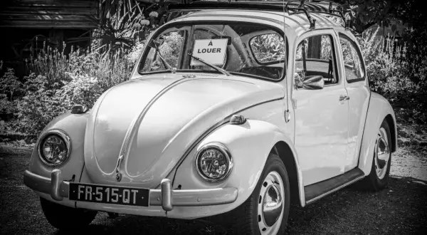 Klasyczny Volkswagen Garbus z tabliczką "À LOUER" na przedniej szybie. Idealny do kupna samochodu na wakacje.