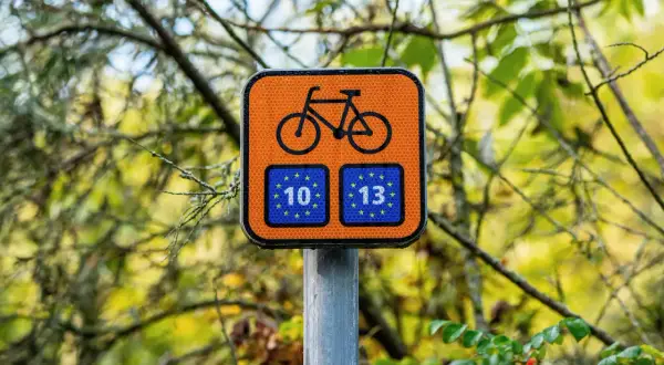 Pomarańczowy znak rowerowy z numerami 10 i 13, wskazujący trasę R10.
