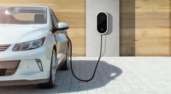 Biały samochód elektryczny podłączony do ładowarki ściennej. Czysta energia dla przyszłości.