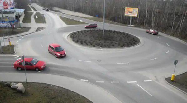 Rondo turbinowe jak jeździć? Czerwone samochody poruszają się po wielopasmowym rondzie, pokazując płynność ruchu.