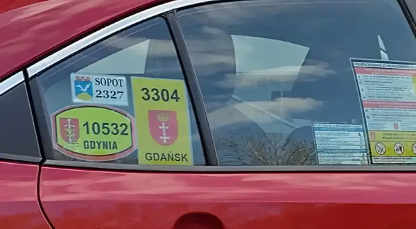 Naklejki taksówkarskie z numerami i herbami miast: Sopot, Gdynia, Gdańsk na czerwonym samochodzie.