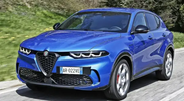 Niebieski Alfa Romeo Tonale pędzi po drodze. Wśród wielu marek samochodów alfabetycznie, ten włoski SUV wyróżnia się dynamicznym designem.