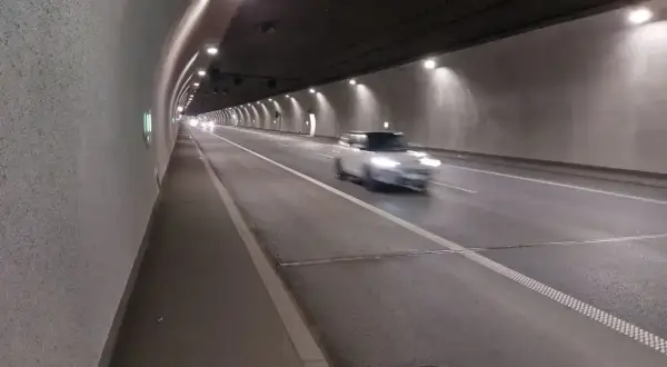 Biały samochód mknie przez oświetlony tunel zakopianka.