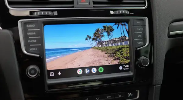 Samochód z ekranem Android Auto aktualizacja. Widok na tropikalną plażę z palmami.