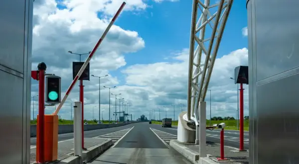 Brama na autostradzie A4 otwarta, zielone światło. Droga prowadzi w dal pod błękitnym niebem z chmurami.