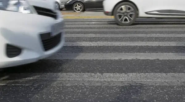 Samochody jadące na pasach. Jeden z nich wyprzedza, tworząc dynamiczną scenę na drodze.