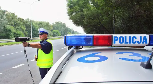 Policjant mierzy prędkość. Uważaj na drogach, bo za przekroczenie limitu możesz dostać sporo punktów karnych.