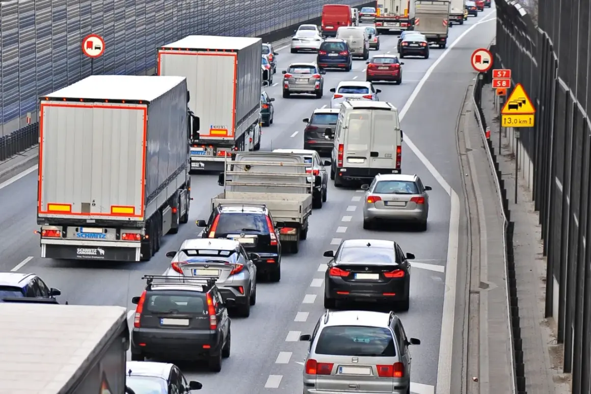 Kork na autostradzie, gdzie trwa jazda na suwak. Samochody i ciężarówki stoją w długim korku.