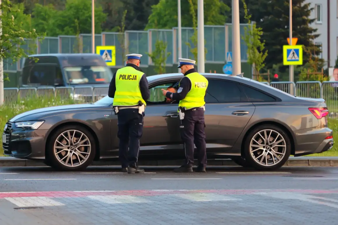 Policjanci w kamizelkach odblaskowych rozmawiają z kierowcą przy samochodzie. Może to być kontrola drogowa lub przygotowanie do odwołania od mandatu.