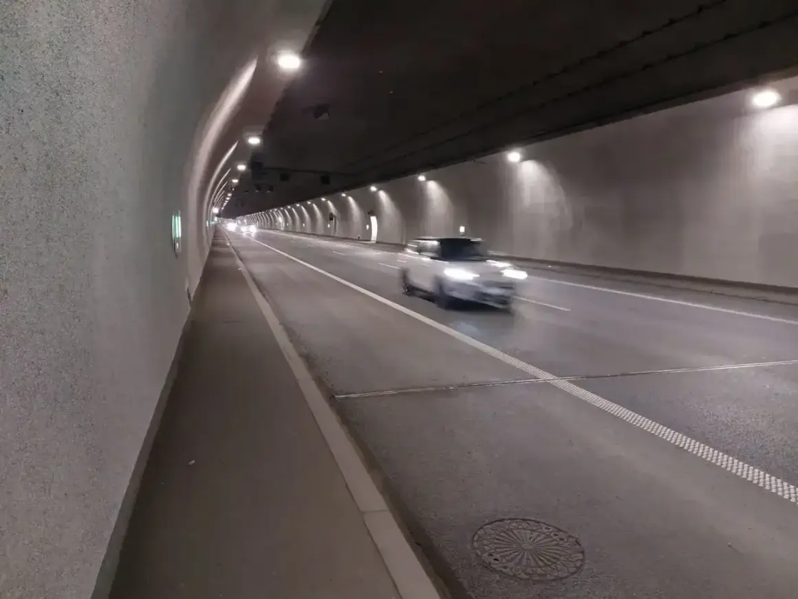 Biały samochód mknie przez oświetlony tunel zakopianka.