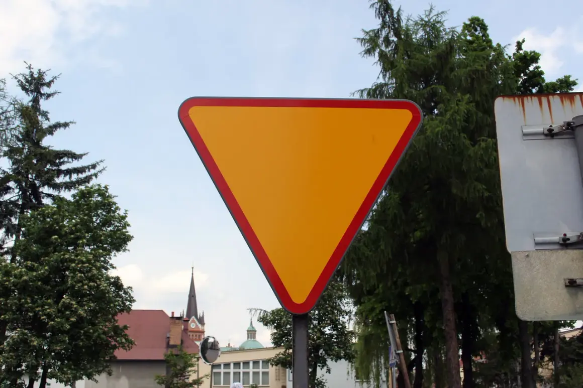 Żółty trójkątny znak a7 z czerwoną obwódką, ostrzegający o ustąpieniu pierwszeństwa.