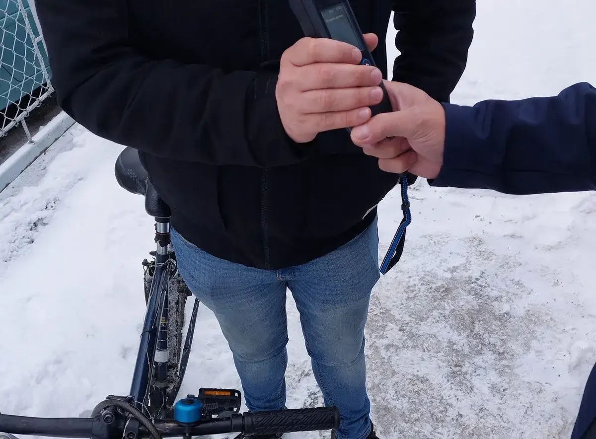 Policjant bada alkomatem rowerzystę w zimowy dzień. Jazda rowerem po alkoholu to niebezpieczny pomysł.