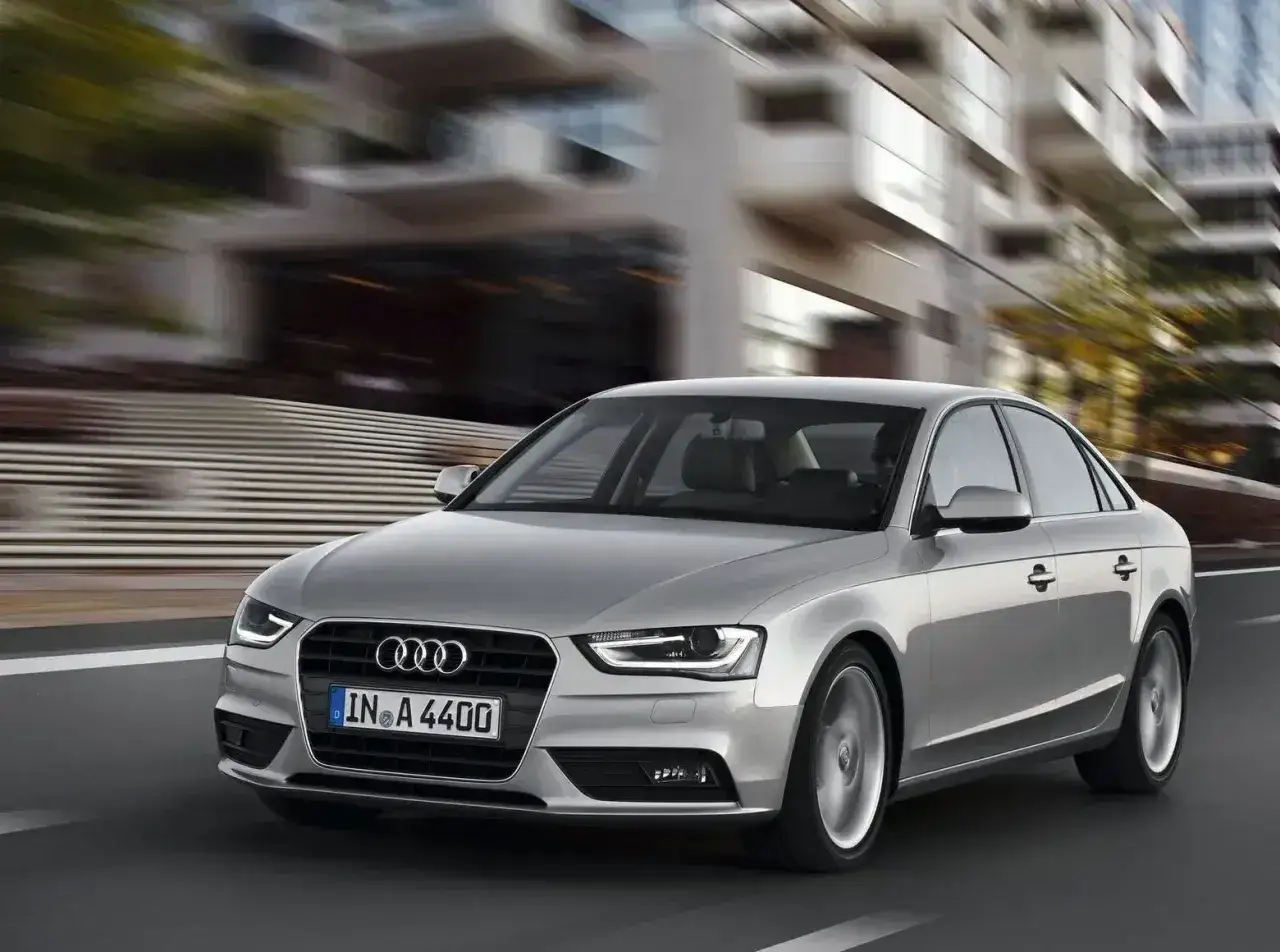Srebrne Audi A4 B8 w ruchu miejskim, z widocznymi typowymi usterkami tego modelu, jak np. problemy z elektroniką.