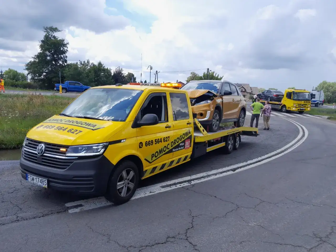 Żółta laweta z uszkodzonym złotym SUV-em na pokładzie. Obok stoi drugi holownik. Zastanawiasz się, ile kosztuje laweta?
