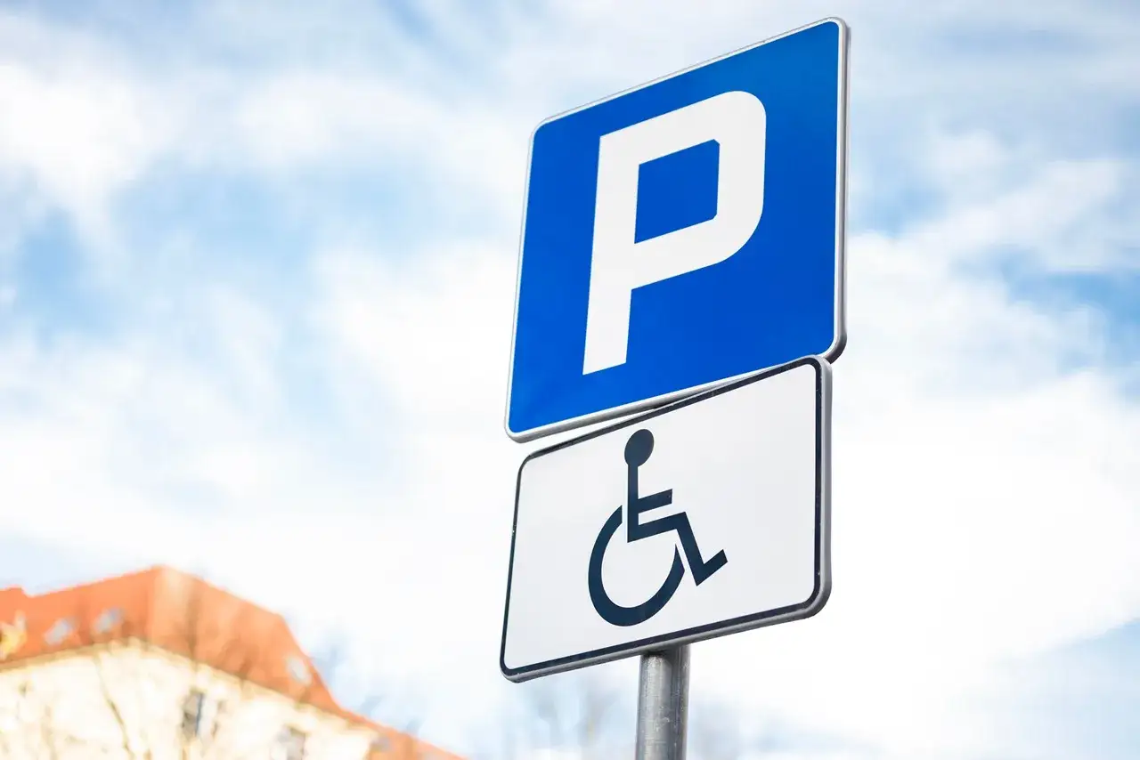 Znak parkingu dla osób niepełnosprawnych na drodze wewnętrznej. Niebieski znak z białą literą 
