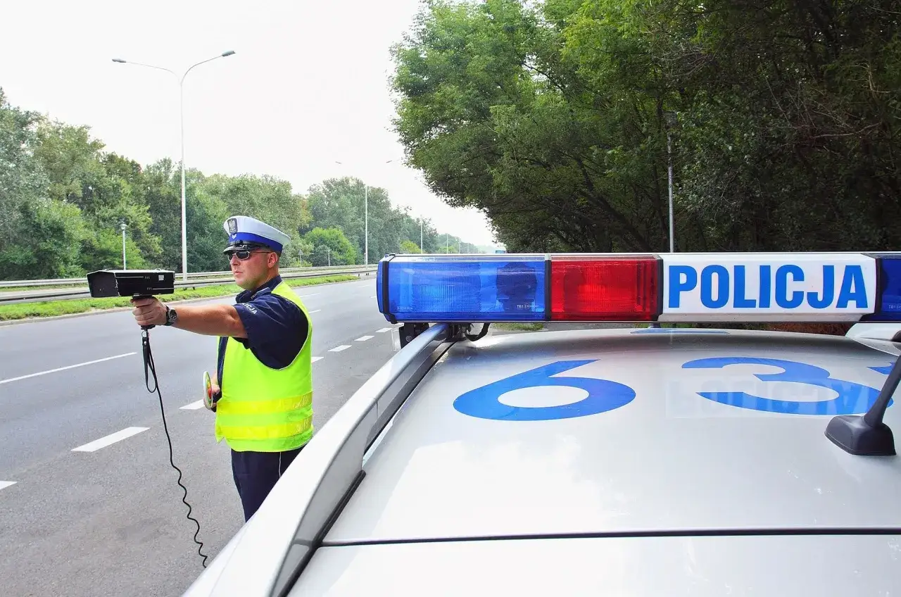 Policjant mierzy prędkość. Uważaj na drogach, bo za przekroczenie limitu możesz stracić prawo jazdy i dostać sporo punktów karnych.