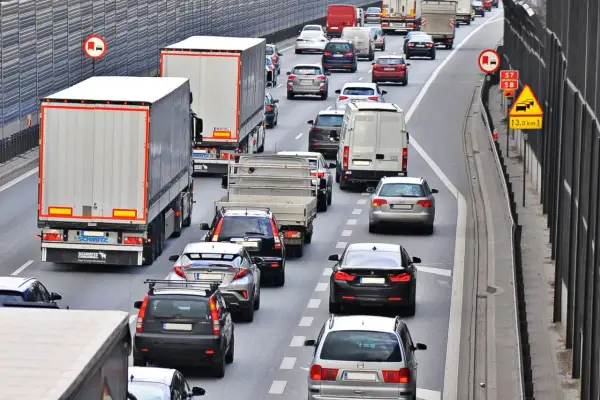 Kork na autostradzie, gdzie trwa jazda na suwak. Samochody i ciężarówki stoją w długim korku.