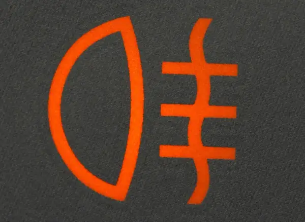 Pomarańczowy symbol świateł do jazdy dziennej na ciemnym tle.