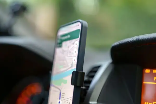 Smartfon z mapą na ekranie, zamontowany w samochodzie. To darmowa nawigacja samochodowa, która ułatwia podróżowanie.