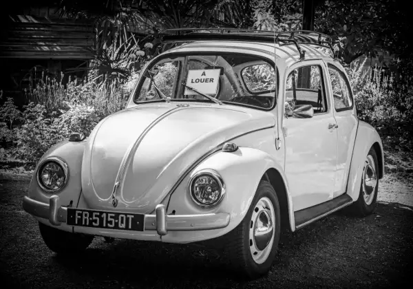 Klasyczny Volkswagen Garbus z tabliczką "À LOUER" na przedniej szybie. Idealny do kupna samochodu na wakacje.