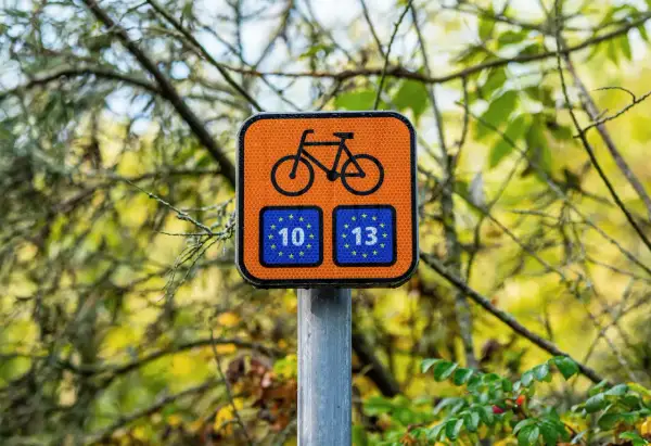 Pomarańczowy znak rowerowy z numerami 10 i 13, wskazujący trasę R10.